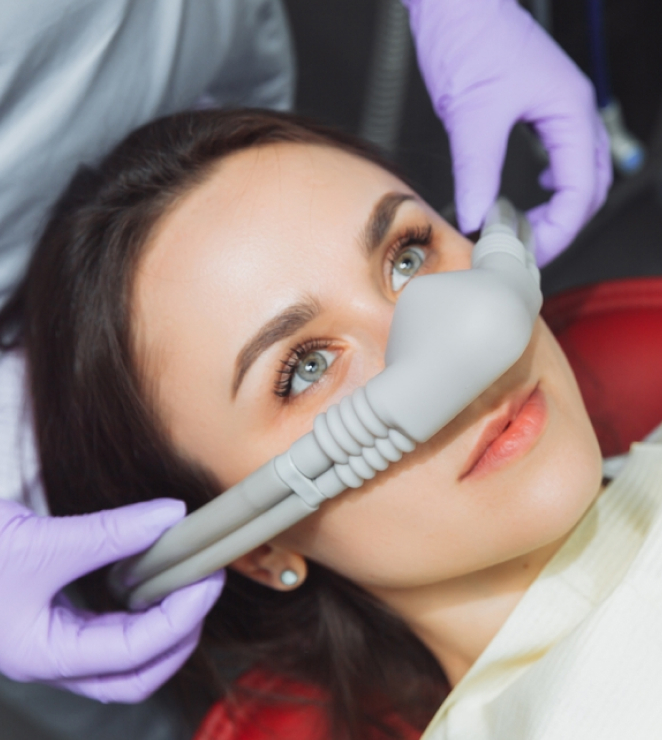 Woman receiving dental treatment with intraoral scanner device in clinical setting.