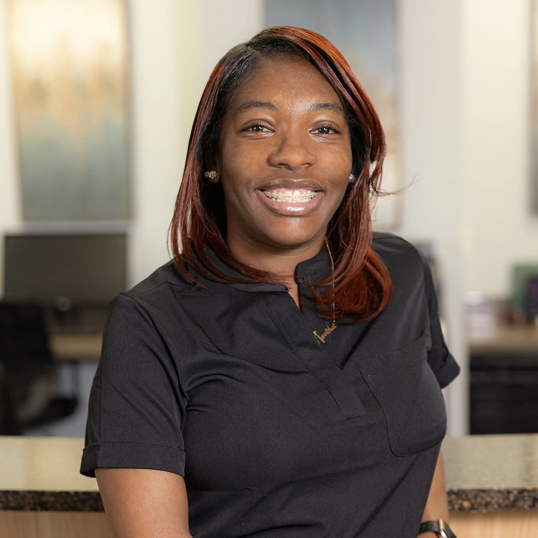 Professional woman smiling in modern dental office setting wearing black shirt